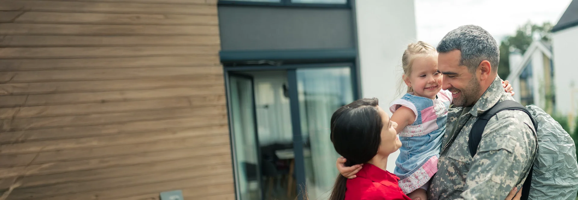 A soldier stands proudly with his family outside their home